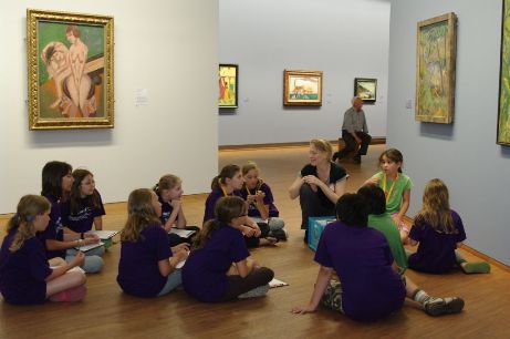Kinder sitzen im Museum und schauen auf die Bilder